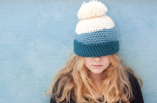 Teenager with hat pulled over her eyes. Space for text