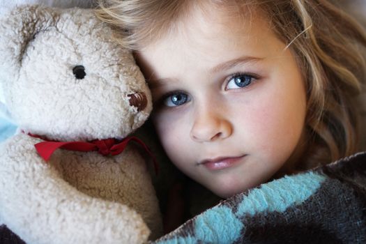 A child wrapped up in blanket with soft toy