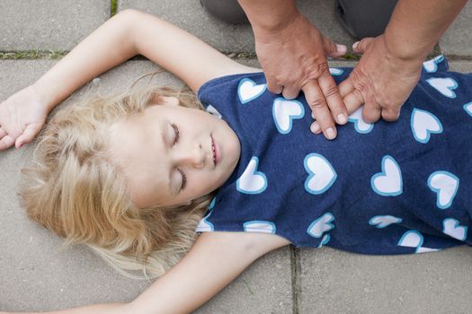 A little girl receiving first aid heart massage by nurse or doctor or paramedic