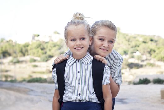 Two blond school girls with school bag and school uniforms