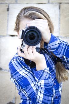 A young woman holding a camera in frontof her face