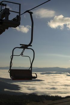 Seat elevator in the mountains above the white clouds