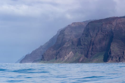 Rugged mountains and cliffs of Na Pali coast in Kauai seen from a cruise boat in winter