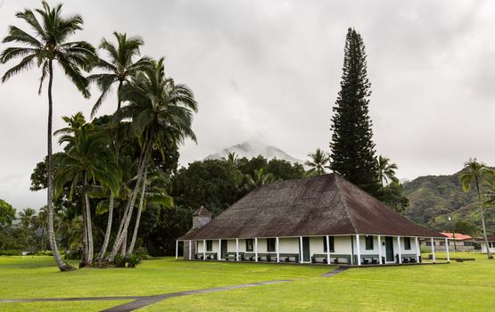 The old Waioli Huiia Mission building and hall in Hanalei Kauai with the Na Pali Mountains shrouded in mist in the background