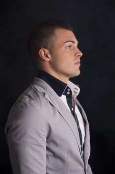 Profile view of elegant handsome young man with shirt and jacket, dark background