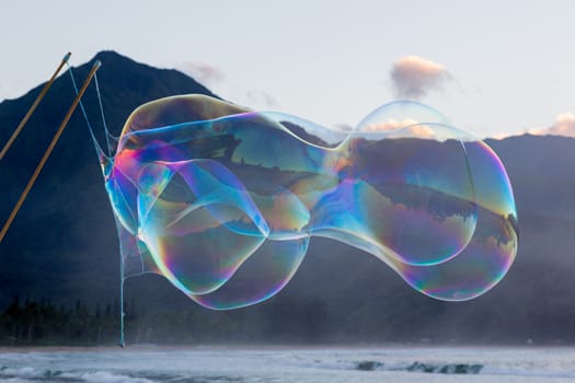 Man making multiple giant soap bubbles on Hanalei beach in Kauai Hawaii