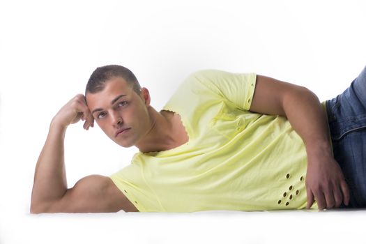 Handsome, muscular young man leaning on the floor, head against his hand
