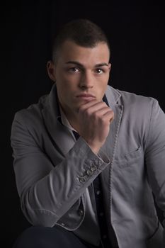 Portrait of handsome young man with shirt and jacket, holding chin with his hand, looking at camera