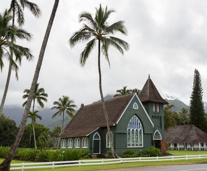 The old Waioli Huiia Mission church building and hall in Hanalei Kauai with the Na Pali Mountains shrouded in mist in the background