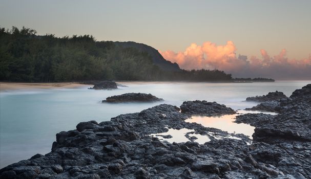 Rocks and rockpools lead into the blurred motion of the waves and ocean at Lumahai Beach in Kauai in Hawaiian islands
