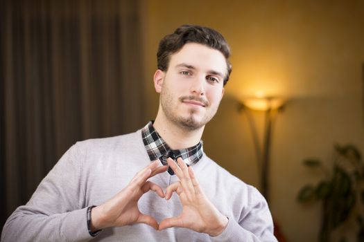 Handsome young man making heart sign with his hands and fingers