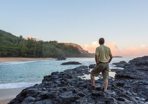 Senior caucasian man overlooks the rocks and ocean at Lumahai Beach in Kauai in Hawaiian islands