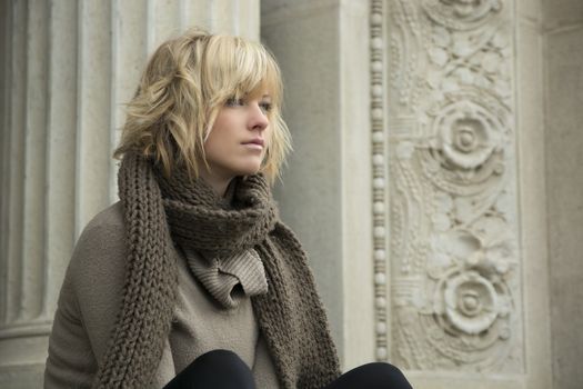 Attractive blonde young woman looking off camera, marble column and decorations behind her