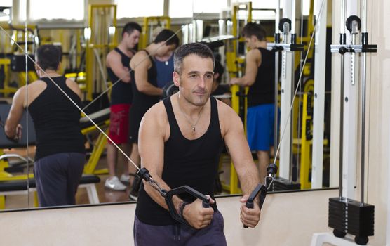 Middle aged man working out with gym equipment, exercising pecs muscles with cables