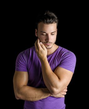 Sad or worried handsome young man looking down, isolated on black background