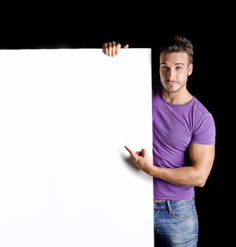 Handsome young man with large blank display or board, on black background