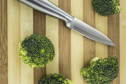 Fresh broccoli on wood with knife.