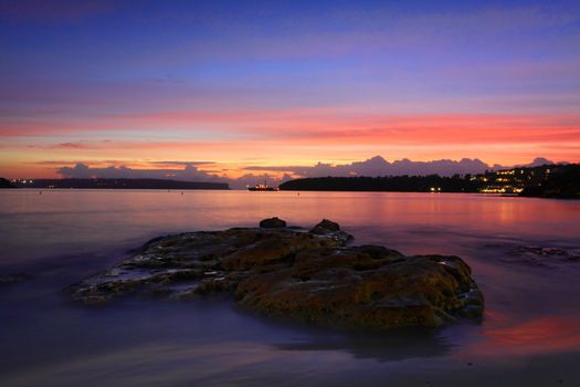 Dawn glow at Edwards Beach NSW Australia.  A fishing trawler silhouetted between the view to Sydney Heads.