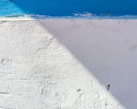White and blue painted wall, part in the sun part in the shade