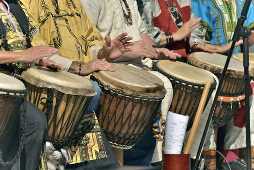 men and famme play djembe outside