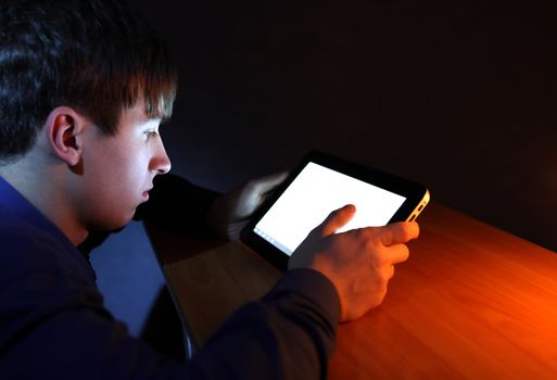 Teenager with Tablet Computer in the Dark Room