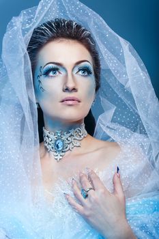 Attractive young girl with a theatrical makeup on the face in the image fabulous snow queen