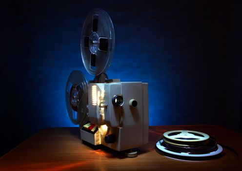 Old 8mm film projector in dusk beside a stack of film reels