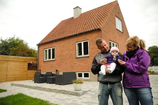 Happy family is standing in front of a house.