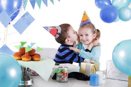 Two children celebrating birthday at party table over white