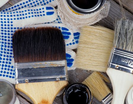 Arrangement of Various Oil Colors, Paint Brushes and Protective Gloves closeup on Wooden background. Top View