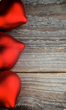 Frame of Three Red Plastic Hearts closeup on Rustic Wood background