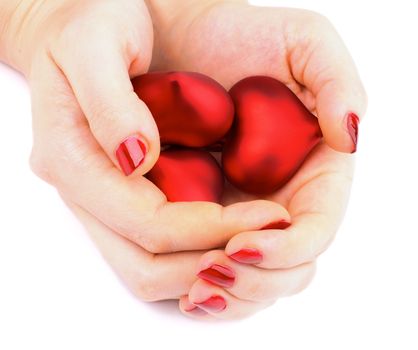 Arrangement of Three Shiny Plastic Hearts in Woman Hands with Red Manicure isolated on white background
