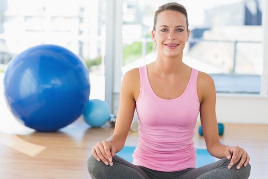 Portrait of a smiling young woman sitting at a bright fitness studio