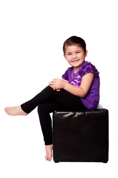 Cute adorable happy smiling laughing giggling girl sitting on ottoman, isolated.
