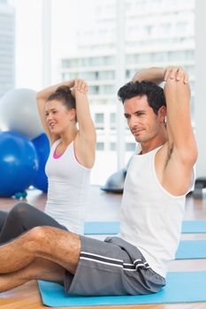 Two sporty people stretching hands at yoga class in fitness studio
