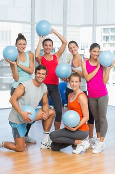 Portrait of happy fit young people with balls in a bright exercise room