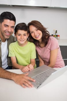 Portrait of a smiling couple with young son using laptop at home