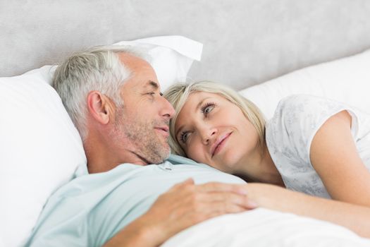 Closeup of a loving mature man and woman lying in bed at the home