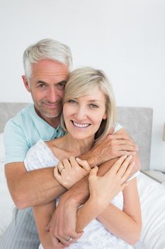 Closeup portrait of a loving mature man embracing woman in bed at home
