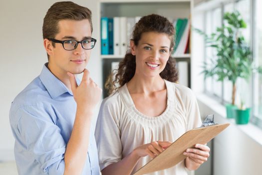 Portrait of confident business people with clipboard in office