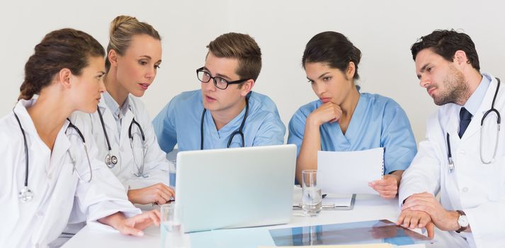 Medical team discussing over laptop in hospital