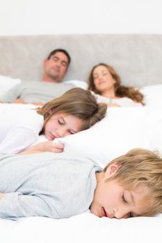 Siblings and parents resting in bed