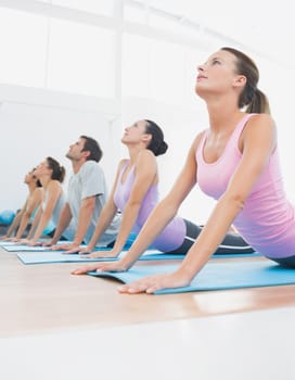 Side view of a fit class exercising in row at fitness studio