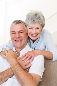 Portrait of happy senior woman embracing husband in house