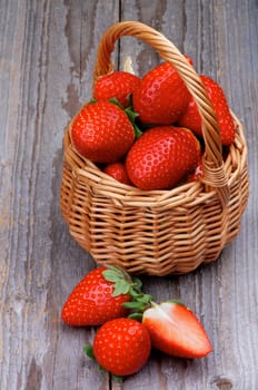 Wicker Basket with Fresh Ripe Strawberries closeup on Rustic Wooden background