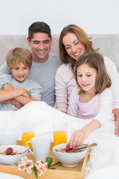 Smiling family having breakfast in bed