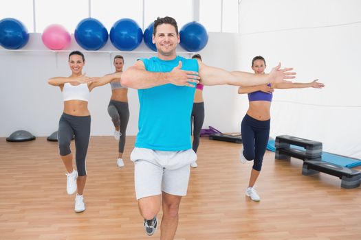 Portrait of smiling people doing power fitness exercise at yoga class in fitness studio