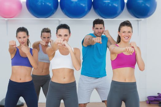 Portrait of smiling people doing power fitness exercise at yoga class in fitness studio