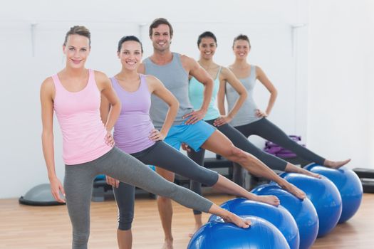 Portrait of an instructor and fitness class with exercise balls at fitness studio