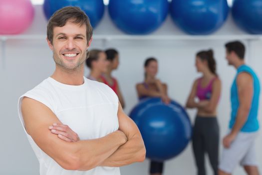 Portrait of a fit young man with friends in background at fitness studio